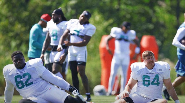 Aug 8, 2025; Lake Forest, IL, USA; Miami Dolphins guard Germain Ifedi (62) and offensive tackle Daniel Brunskill (64) stretch during joint training camp practice with the Chicago Bears ahead of Sunday&#39;s preseason opener. Mandatory Credit: Kamil Krzaczynski-Imagn Images