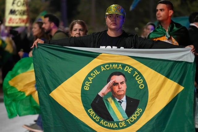 Demonstrators rally in support of former President Jair Bolsonaro at the entrance to his residential complex, to denounce his house arrest order by the Supreme Court, in Brasília, Brazil, Tuesday, Aug. 5, 2025. (AP Photo/Eraldo Peres)
