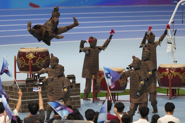 A human performer leaps above robots dressed like terracotta warriors during the opening ceremony of The World Humanoid Robot Games held in Beijing, China, Thursday, Aug. 14, 2025. (AP Photo/Ng Han Guan)