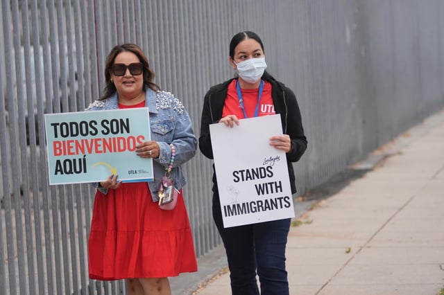 La profesora Nancy Barba, izquierda, y una de sus colegas docentes sostienen carteles de apoyo a los inmigrantes, durante el primer día del nuevo año académico, el jueves 14 de agosto de 2025, en Los Ángeles. (AP Foto/Marcio Jose Sanchez)