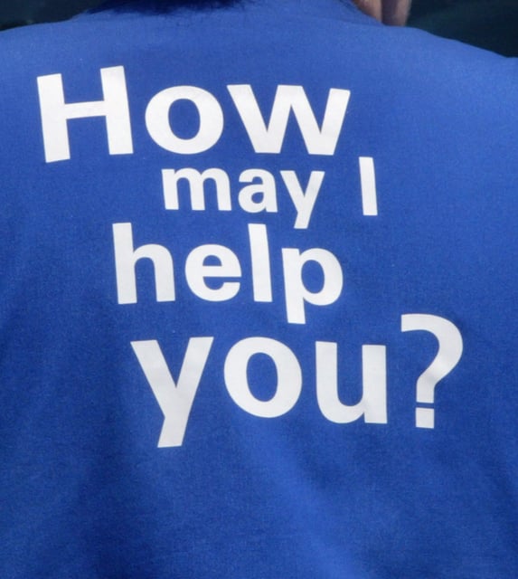 A female Wal-Mart employee's work vest asking "How may I help you?" is seen as she walks through a parking lot returning to work at a Wal-Mart store June 23, 2004 in St. Charles, Illinois.