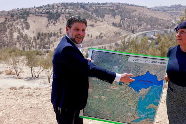 El ministro de Finanzas israelí de extrema derecha, Bezalel Smotrich, sostiene un mapa de un área cercana al asentamiento de Maale Adumim, un corredor terrestre conocido como E1, en las afueras de Jerusalén, en Cisjordania ocupada, el 14 de agosto de 2025