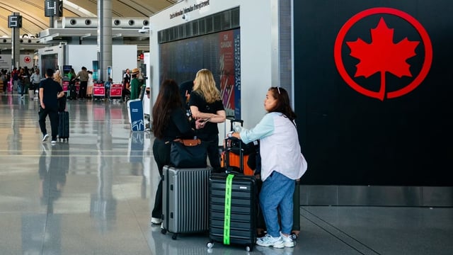 People are seen standing near the Air Canada check-in area inside Terminal 1 of Toronto's Pearson airport on Wednesday.