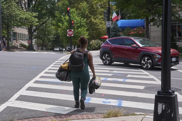 Ms. Jay, of Washington, who lost her job and is living what she calls her "Girl Scout life" while saving money by urban camping and looking for work while homeless, carries her belongings across Pennsylvania Avenue near Georgetown, Wednesday, Aug. 13, 2025, in Washington, after packing her tent after being warned by an aid organization that homeless encampments are being removed. "Last night was so scary," says Ms. Jay, "I don't want to be the one to wait until the last moment and then have to rush out." (AP Photo/Jacquelyn Martin)