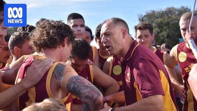 A man in a red and gold guernsey talks to a dozen young men in red and gold guernseys