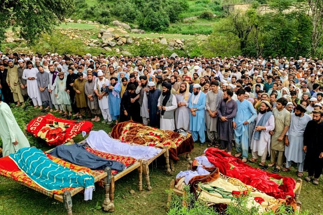 Personnes endeuillées et locaux récitent des prières funéraires pour les victimes décédées lors des crues soudaines dues aux pluies de mousson à Salarzai, dans le district de Bajaur au Pakistan, le 15 août 2025