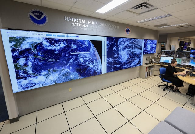 Lisa Bucci, Hurricane Specialist, works near screens showing Tropical Storm Erin as they continue to track its progress on August 13, 2025 at the National Hurricane Center in Miami, Florida.