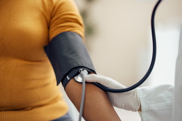 Stock image shows medical professional measuring blood pressure with a manometer.