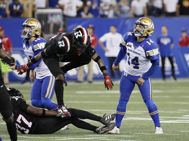 Winnipeg Blue Bombers kicker Sergio Castillo (14) and Jamieson Sheahan (left) watch as Castillo's kick goes through the uprights for the game-winning field goal against the Ottawa Redblacks.