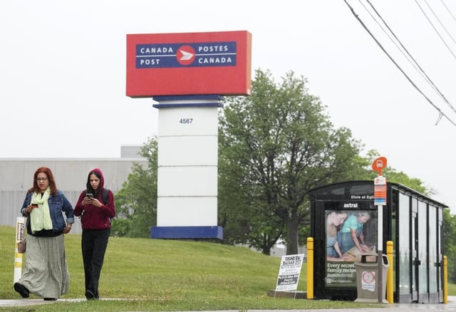 People walk past the Canada Post facility in Mississauga, Ont., on May 22, 2025. Canada Post could go on strike this Friday.