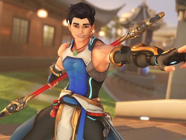 Overwatch 2 Wuyang hero trial preview: Wuyang posing on a bridge, smiling as he points forward with his left and while his right hand is behind his back holding his staff.