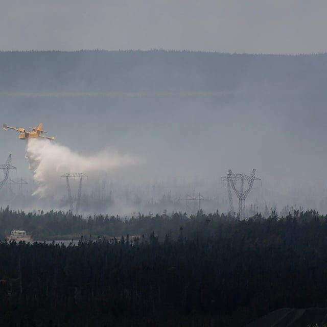 A water bomber provides a steady steam of water to assist crews on the ground at the Paddy's Pond wildfire, just outside St. John's, N.L., on Thursday, Aug. 14, 2025. THE CANADIAN PRESS/Paul Daly