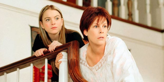 Lindsay Lohan holding onto a staircase handle next to Jamie Lee Curtis in 'Freaky Friday'.