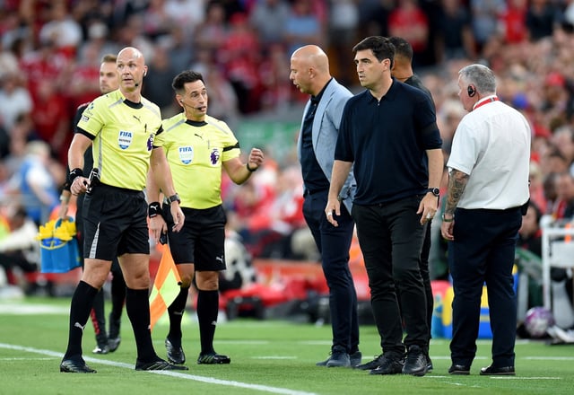 Soccer Football - Premier League - Liverpool v AFC Bournemouth - Anfield, Liverpool, Britain - August 15, 2025 Referee Anthony Taylor looks on with AFC Bournemouth manager Andoni Iraola and Liverpool manager Arne Slot after the game was paused due to a report of racial abuse from the crowd by AFC Bournemouth's Antoine Semenyo REUTERS/Peter Powell