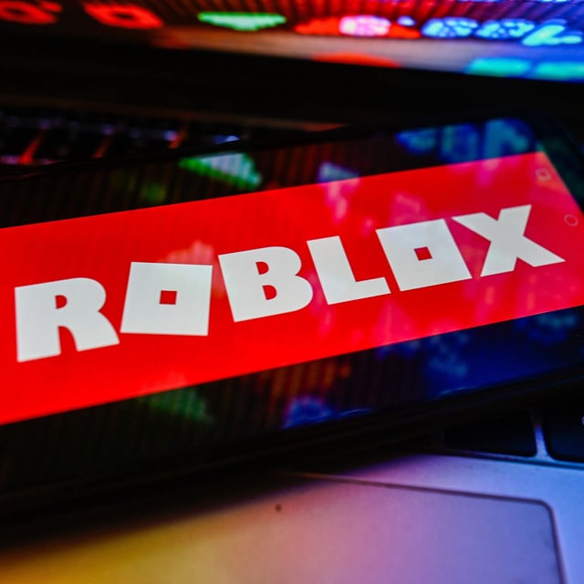 POLAND - 2023/11/09: In this photo illustration a Roblox logo is displayed on a smartphone with stock market percentages on a laptop. (Photo Illustration by Omar Marques/SOPA Images/LightRocket via Getty Images)
