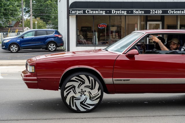 A driver puts up a peace sign while driving through Woodward Avenue during the 2024 Woodward Dream Cruise in Ferndale on Saturday, Aug. 17, 2024.