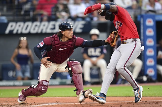 Cleveland Guardians catcher Bo Naylor, left, tags out Atlanta Braves' Jurickson Profar during the third inning of a baseball game, Friday, Aug. 15, 2025, in Cleveland. (AP Photo/David Dermer)