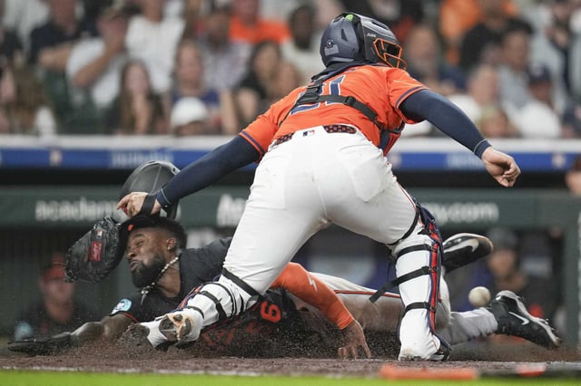 Baltimore Orioles’ Daniel Johnson scores past Houston Astros catcher Yainer Diaz (21) on Gunnar Henderson’s 2-RBI sac-fly during the fifth inning of an MLB baseball game in Houston, Friday, Aug. 15, 2025.