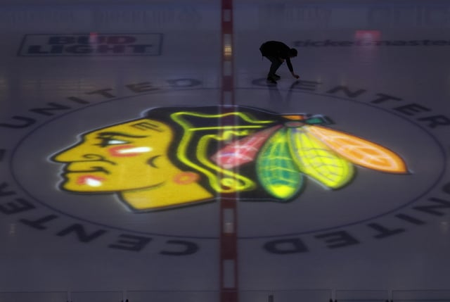 The center ice Blackhawks logo is illuminated as a worker inspects the ice before a game against the Los Angeles Kings at the United Center on March 15, 2024, in Chicago. (John J. Kim/Chicago Tribune)