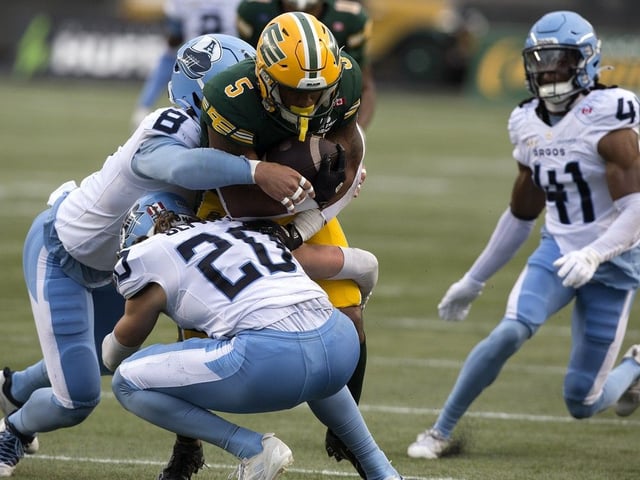 The Edmonton Elks' Justin Rankin (5) is tackled by the Toronto Argonauts' Cameron Judge (8) and Derek Slywka (20) during CFL action at Commonwealth Stadium, in Edmonton Friday Aug. 15, 2025. 