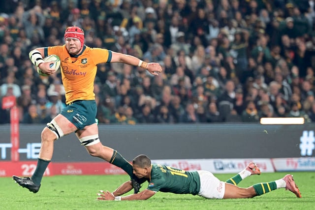 Harry Wilson corre con la pelota y marcará un try para Australia, pese al intento de Manie Libbok por detenerlo