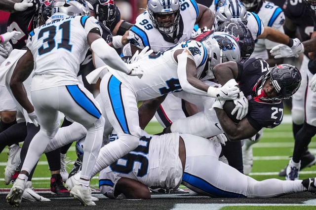 Houston Texans running back Woody Marks (27) dives through the Carolina Panthers defense for a short gain during the first half of a preseason NFL football game at NRG Stadium in Houston, Saturday, Aug. 16, 2025.