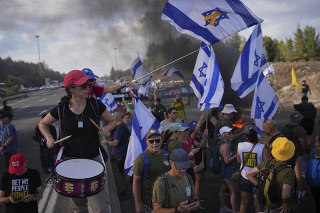 Demonstrators block a road during a protest demanding the immediate release of hostages held by Hamas and calling for the Israeli government to reverse its decision to take over Gaza City and other areas in the Gaza Strip, near Jerusalem, Israel, Sunday, Aug. 17, 2025. (AP Photo/Ohad Zwigenberg)