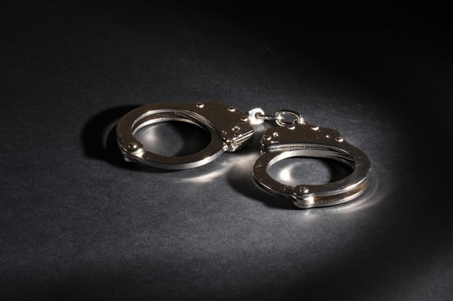 Handcuffs with reflection of lights on a dark background.