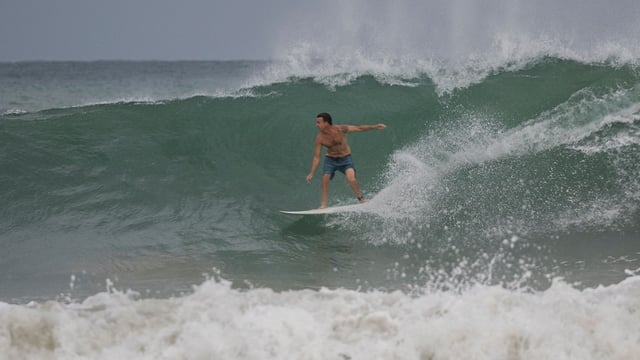 A surfer rides a wave at La Pared beach as Category 5 Hurricane Erin approaches in Luquillo, Puerto Rico on August 16, 2025. Hurricane Erin rapidly strengthened offshore to a catastrophic Category 5 storm on August 16, as rain lashed Caribbean islands and weather officials warned of possible flash floods and landslides. (Photo by Ricardo ARDUENGO / AFP)