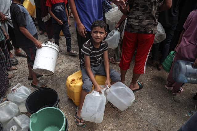 (250802) - GAZA, 2 agosto, 2025 (Xinhua) - Imagen del 1 de agosto de 2025 de un niño palestino desplazado esperando para recolectar agua en un refugio temporal, en la Ciudad de Gaza. (Xinhua/Rizek Abdeljawad) (oa) (da)