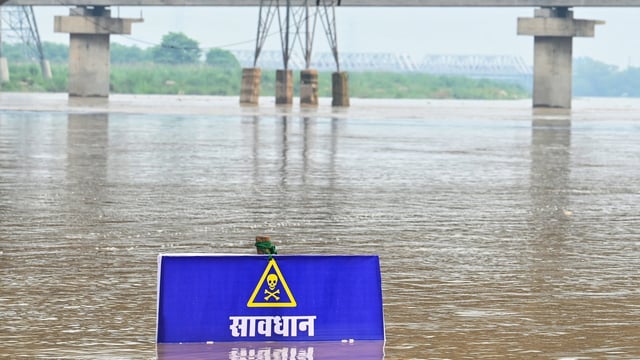 A warning signboard in the Yamuna River near Vasudev Ghat in New Delhi as water levels increase.