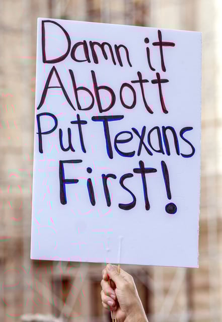 A protester holds up a sign criticizing Texas Gov. Greg Abbott during the Fight The Trump Takeover Rally held at the State Capitol, Saturday, Aug. 16, 2025, in Austin, Texas, to protest congressional redistricting efforts by Texas Republicans and President Donald Trump. (AP Photo/Rodolfo Gonzalez)
