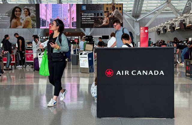 Passengers walk past an Air Canada sign, ahead of a potential strike by flight attendants of the airline, at the Toronto Pearson International Airport in Mississauga, Ontario, Canada, August 14, 2025. REUTERS/Kyaw Soe Oo/File Photo