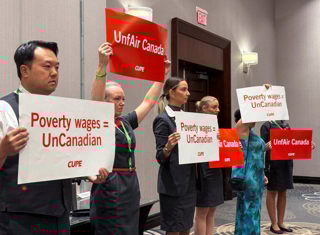 Union activists hold placards, as they interrupt a press conference by Air Canada executives, ahead of a potential strike by Air Canada flight attendants, at a hotel in Toronto, Ontario, Canada, August 14, 2025. REUTERS/Kyaw Soe Oo/File Photo