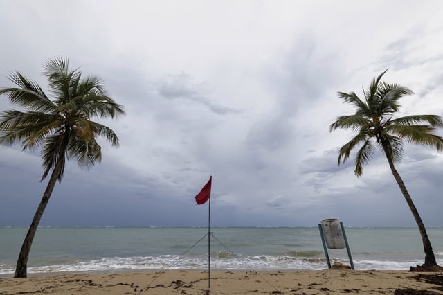 A red flag warns of dangerous waves on an empty beach in San Juan, Puerto Rico, after Hurricane Erin passed by near the island on Sunday, Aug. 17, 2025. (AP Photo/Alejandro Granadillo)