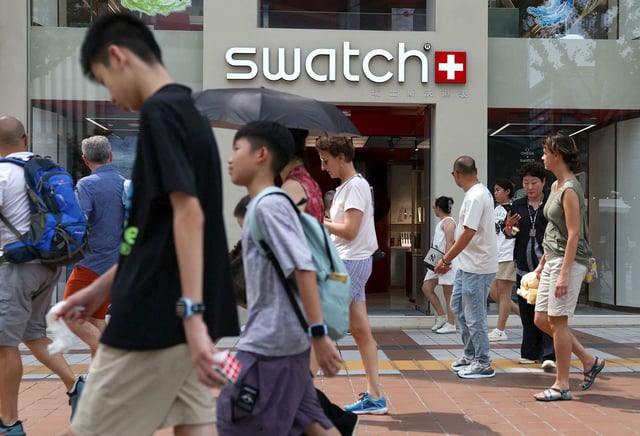 People walk past a store of Swiss watchmaker Swatch, in Beijing, on August 18, 2025.
