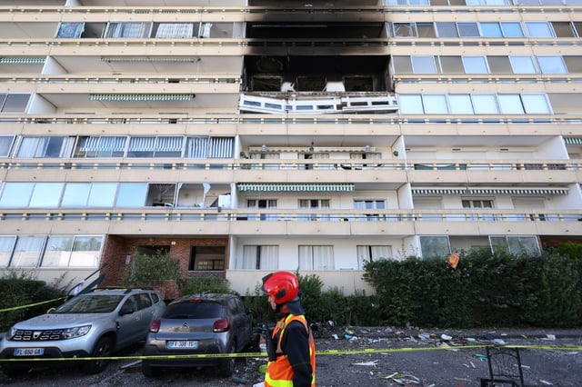 Un pompier passe devant la façade calcinée d'un immeuble suite de l'explosion d'une bouteille de gaz, dans le quartier des Minguettes à Vénissieux, dans la banlieue sud de la ville de Lyon, le 18 août 2025