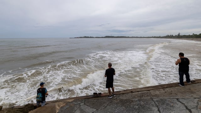 People fish along the shore in Arecibo, Puerto Rico, as Hurricane Erin brings rains to the island, Sunday, Aug. 17, 2025. (AP Photo/Alejandro Granadillo)