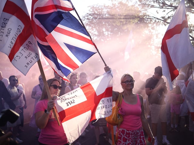 TOPSHOT - Protesters calling for the closure of The Bell Hotel, believed to be housing asylum seekers, gather outside, in Epping, northeast of London, on August 8, 2025. (Photo by HENRY NICHOLLS / AFP) (Photo by HENRY NICHOLLS/AFP via Getty Images)