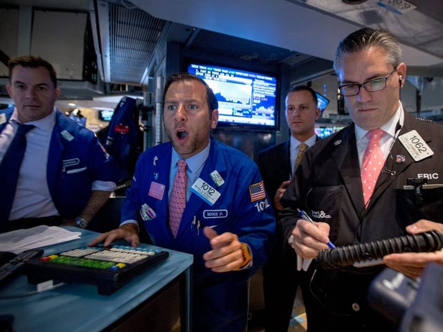 Specialist trader Michael Pistillo (2nd L) gives a price for a stock just after the opening bell on the floor of the New York Stock Exchange August 28, 2014.