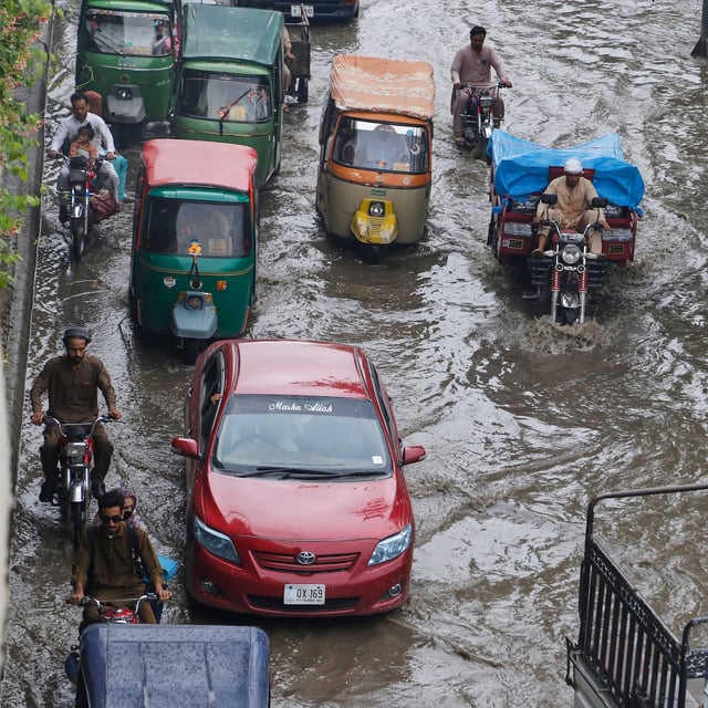 Vehicles and motorcyclists drive through a flooded road after heavy rainfall in Peshawar, Pakistan. Intense rain in the country has claimed lives and spread destruction in several northern districts.