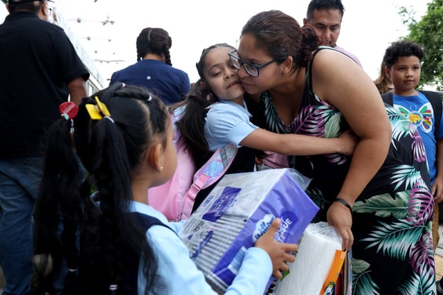 Delia Cruz kisses her daughters, Jadelinn, 8, and Jayne, 5, second left, as they arrive for the first day of school at Edward Sadlowski Elementary School in Chicago on Aug. 18, 2025.  (Antonio Perez/Chicago Tribune)
