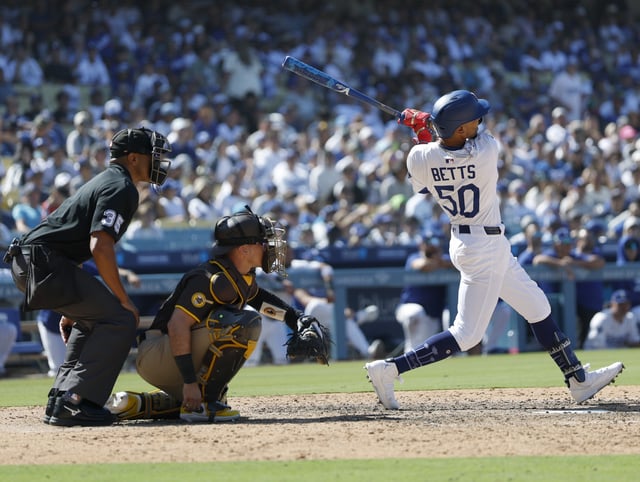 LOS ANGELES, CALIFORNIA - AUGUST 17: Mookie Betts #50 of the Los Angeles Dodgers hits a solo home run in front of Freddy Fermin #54 of the San Diego Padres and umpire Jeremie Rehak #35, to take a 5-4 lead, during the eight inning in the game between the San Diego Padres and the Los Angeles Dodgers at Dodger Stadium on August 17, 2025 in Los Angeles, California.
