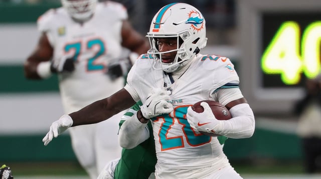 Jan 5, 2025; East Rutherford, New Jersey, USA; Miami Dolphins running back De&#39;Von Achane (28) runs with the ball while New York Jets cornerback D.J. Reed (4) attempts to tackle him during the first quarter at MetLife Stadium. Mandatory Credit: Ed Mulholland-Imagn Images