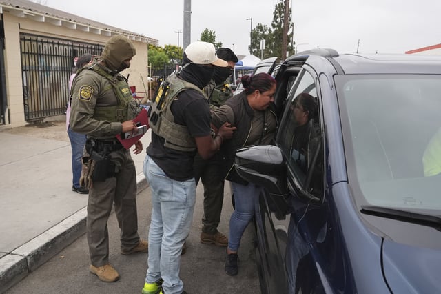 A woman is detained by U.S. Border Patrol agents outside a Home Depot Friday, Aug. 15, 2025, in Los Angeles. (AP Photo/Gregory Bull)