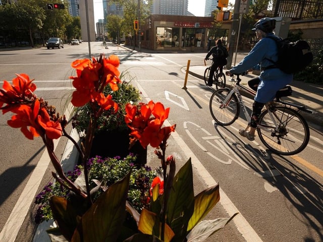  Cyclists ride past flowers in the bike lane at 107 Street and 102 Avenue in Edmonton, on Tuesday, Aug. 20, 2019.