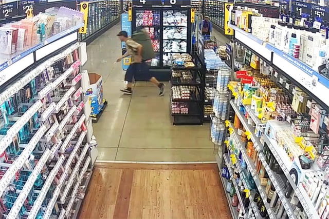 Suspect Bradford James Gille carries a knife while running inside a Walmart near Traverse City, Mich., on July 26.