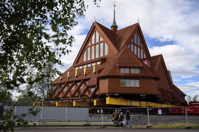 People look at the Kiruna Church, a Sami style wooden Swedish Lutheran church, called Kiruna Kyrka in Swedish, in Kiruna, Sweden, Monday, Aug. 18, 2025, a day before it will be moved along a 5-kilometer (3-mile) route east to a new city center as part of the town's relocation.(AP Photo/Malin Haarala)