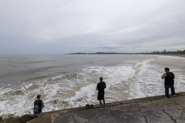 People fish along the shore in Arecibo, Puerto Rico, as Hurricane Erin brings rains to the island, Sunday, Aug. 17, 2025. (AP Photo/Alejandro Granadillo)