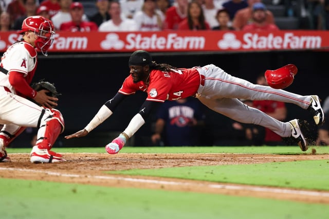 Elly De La Cruz, derecha, de los Rojos de Cincinnati, se barre de cabeza en el plato para anotar carrera mientras Logan O&#39;Hoppe, izquierda, receptor de los Angelinos de Los Ángeles, observa y espera el tiro durante la quinta entrada del juego de béisbol de Grandes Ligas, el lunes 18 de agosto de 2025, en Anaheim, California. (AP Foto/Jessie Alcheh)
